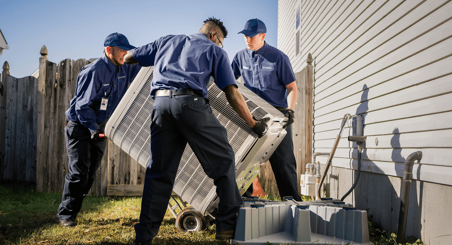HVAC technicians replacing an outdoor residential air conditioning unit.