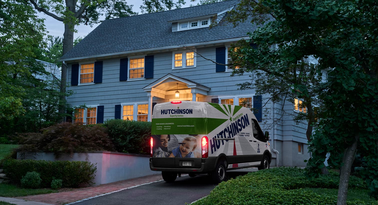 A Hutchinson service van parked in a residential driveway at dusk, arriving to provide 24/7 emergency AC repair services.