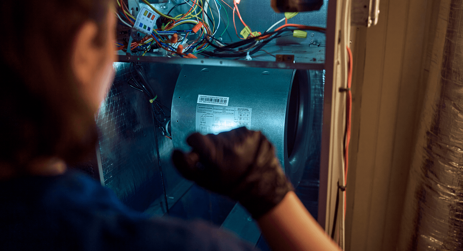 HVAC technician servicing the blower compartment of a residential furnace.
