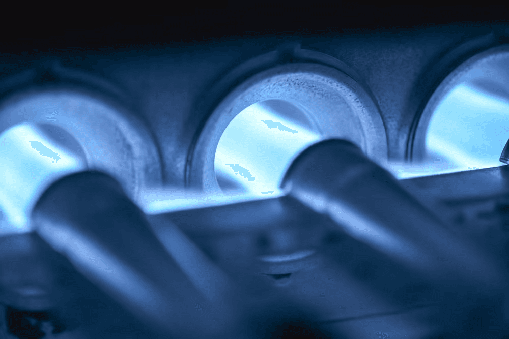 Close-up view of bright blue flames inside a gas furnace burner