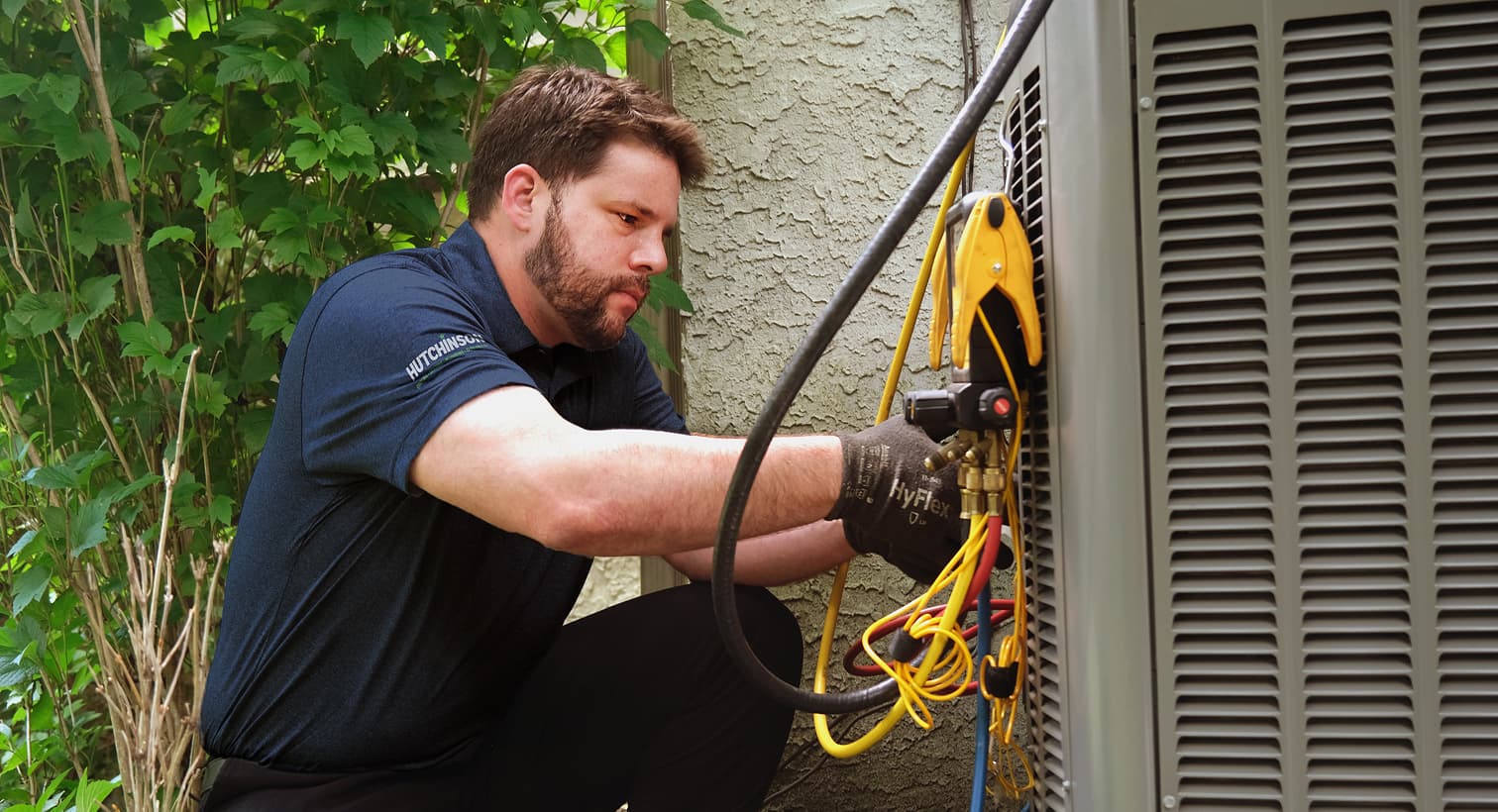 A professional Hutchinson HVAC technician inspecting an outdoor central air conditioning unit to provide residential AC repair and diagnostic services.