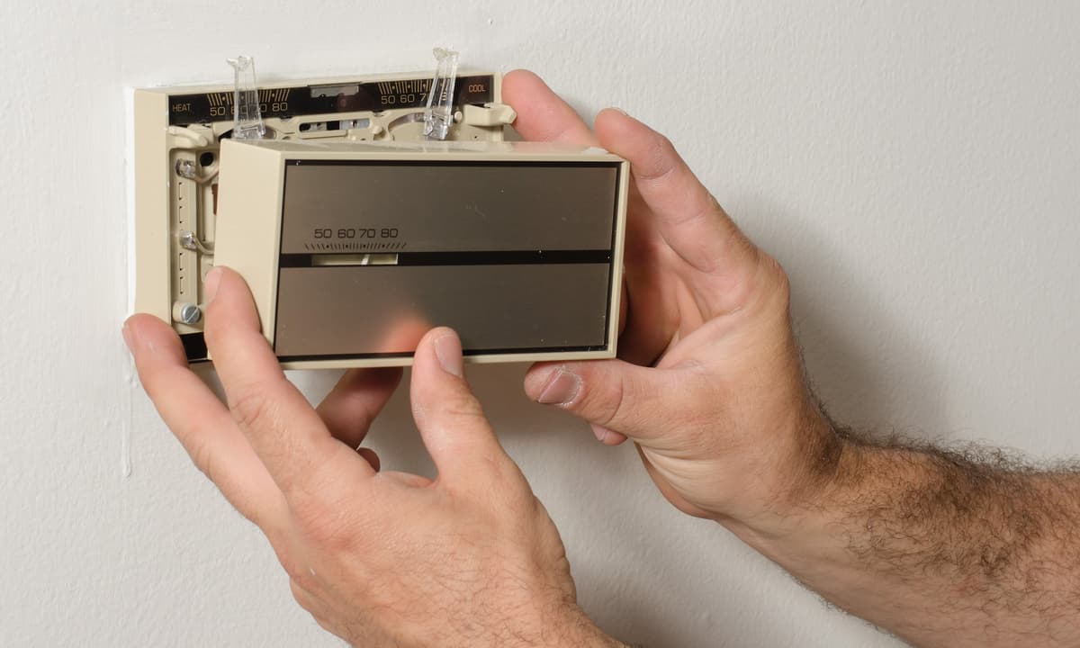 Man holding broken thermostat.
