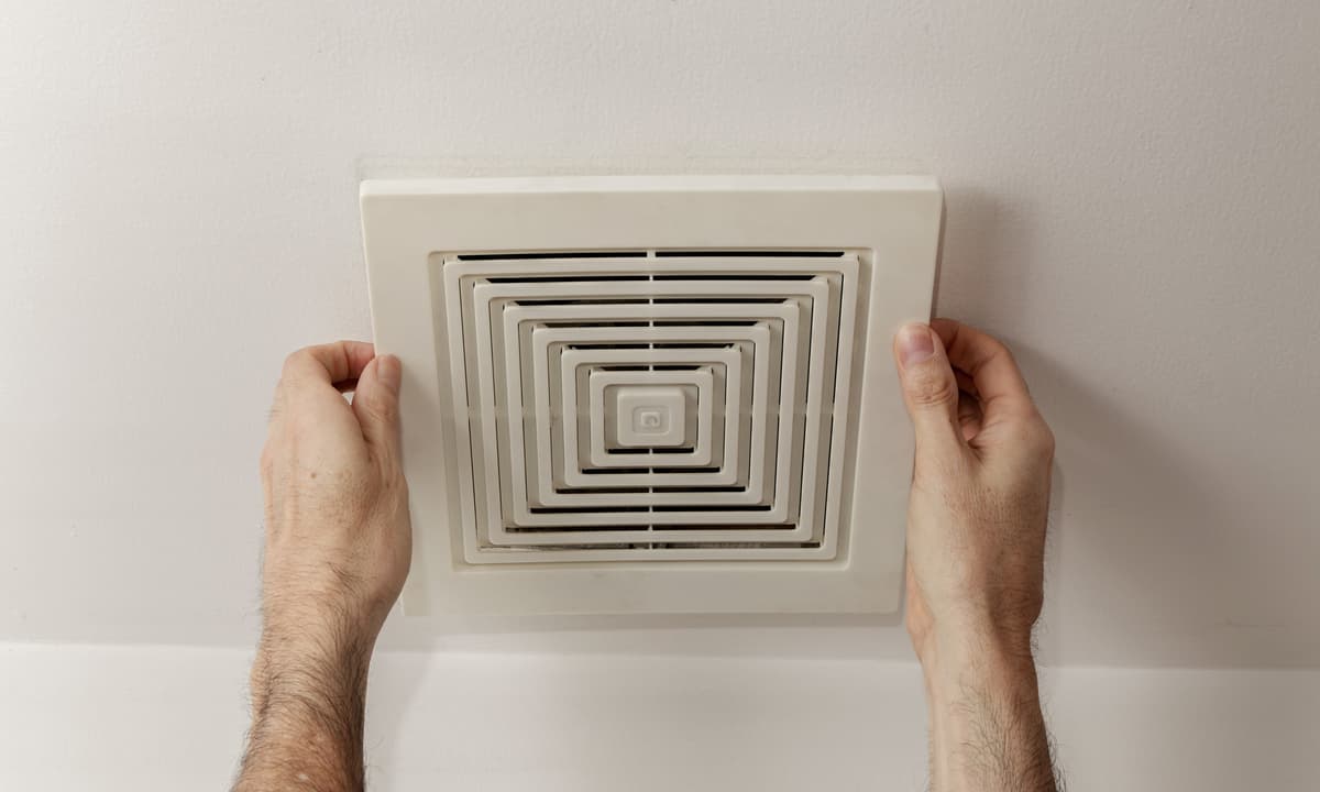 Technician removing bathroom vent cover.