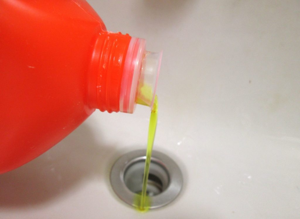 chemical drain cleaner being poured down drain