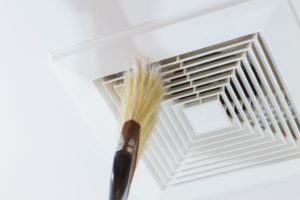 person cleaning indoor air duct with broom